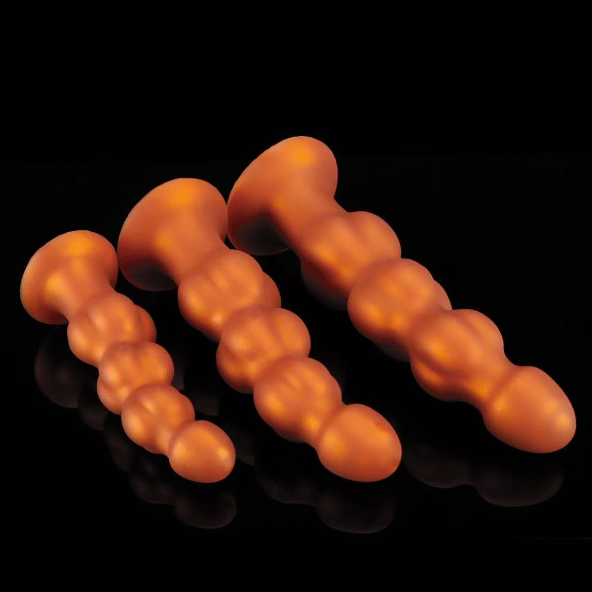 Group display of orange multi-stage bulbous anal plugs.