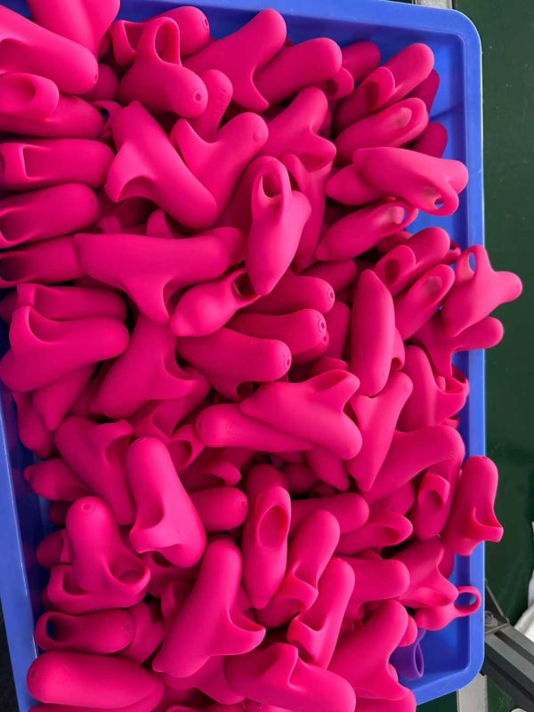 Close-up of pink silicone vibrators in a blue bin, highlighting the smooth texture and ergonomic design of Dongguan Xishang’s products during quality inspection.