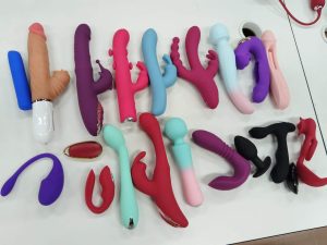 Dongguan Xishang International Trade Co., Ltd. production line featuring multiple bins filled with colorful silicone vibrators in red, pink, and blue, showcasing bulk manufacturing for global export.