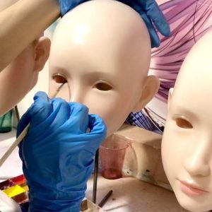 Skilled artisans hand-painting realistic facial details in our intimate product factory