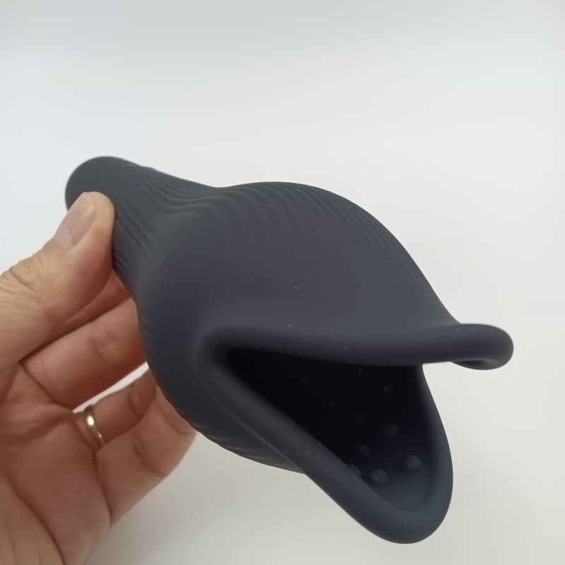Black silicone whale penis trainer held in hand showing its ergonomic opening